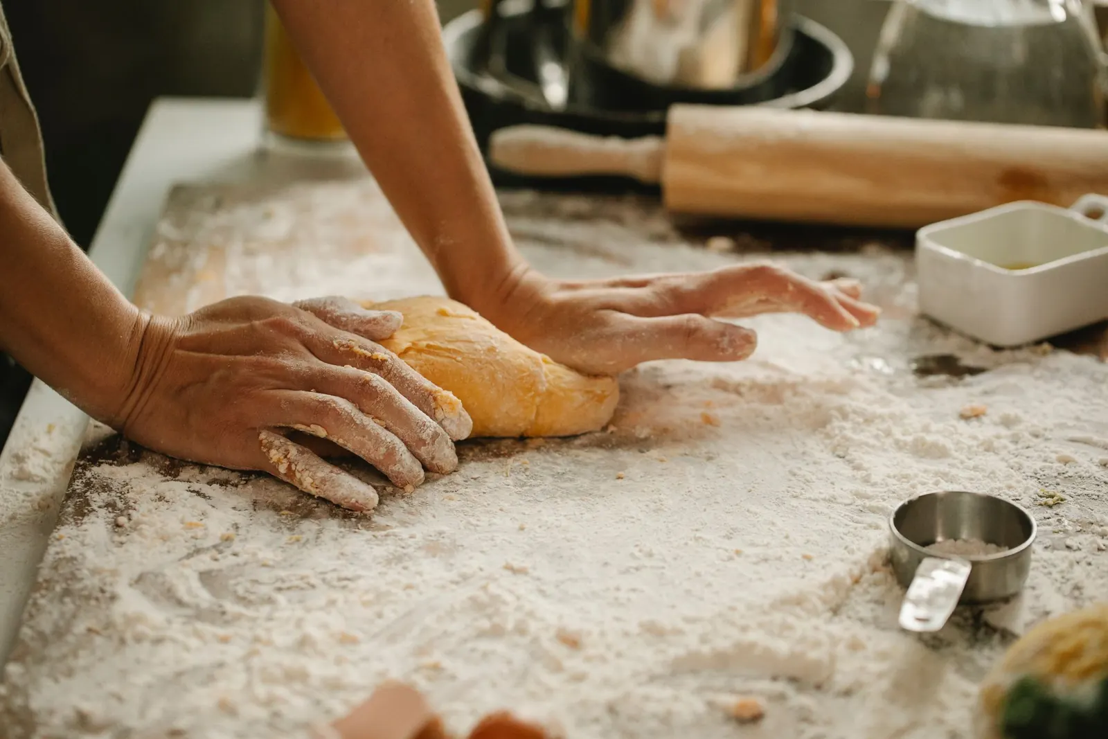 Hands working dough across a floured board