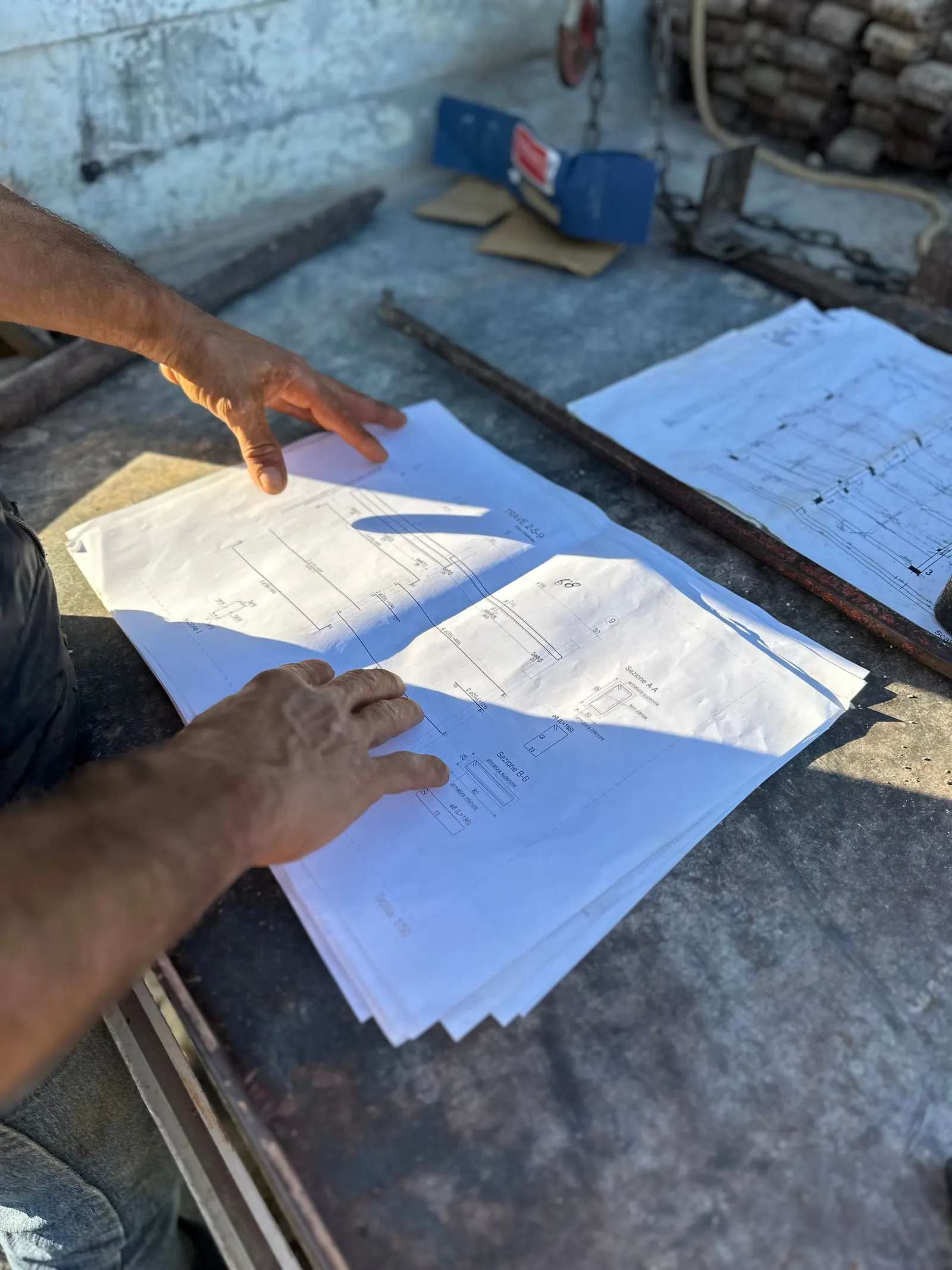 Hands reading construction drawings across a work table