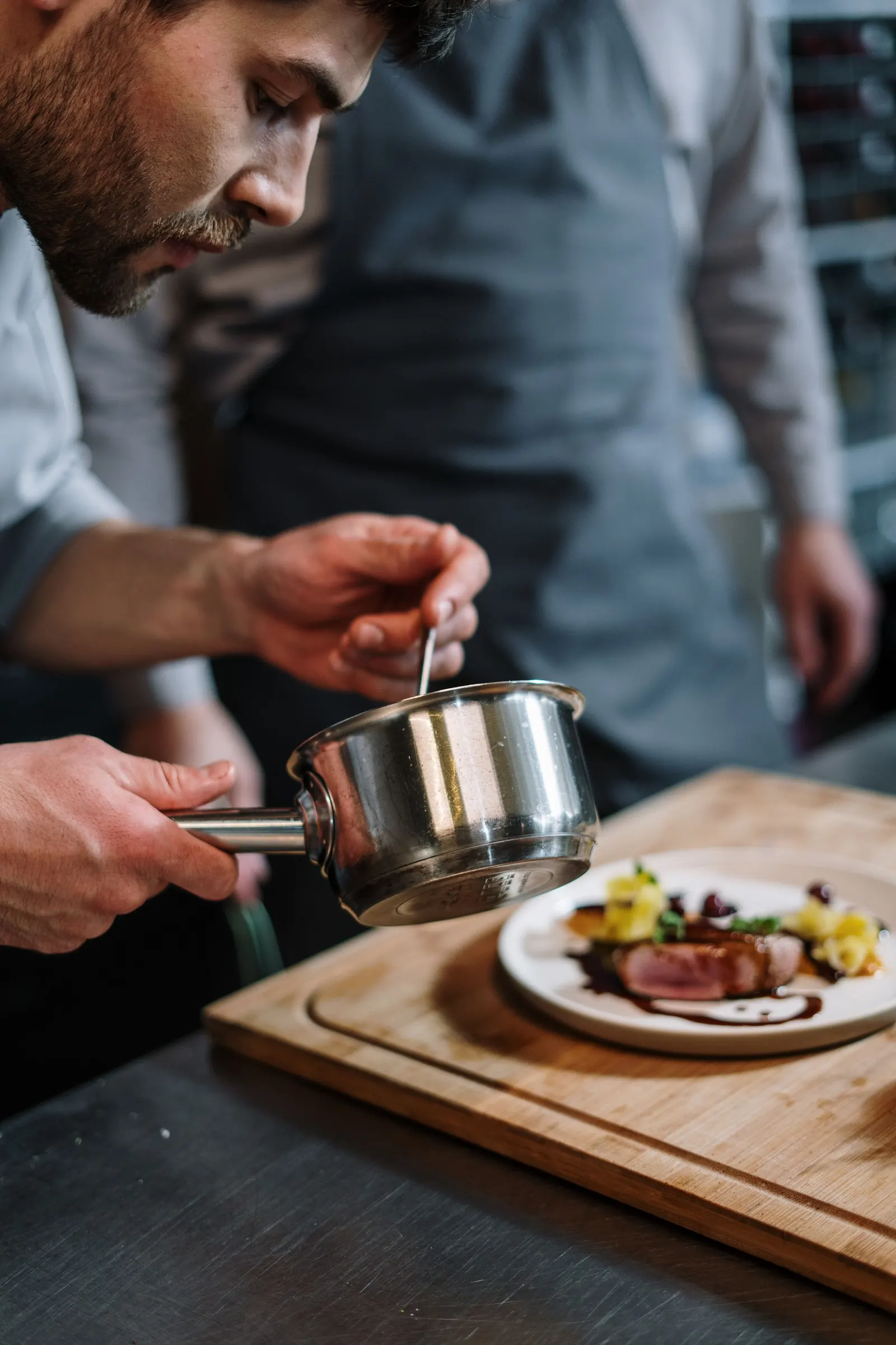 A cook finishing a plate at the pass